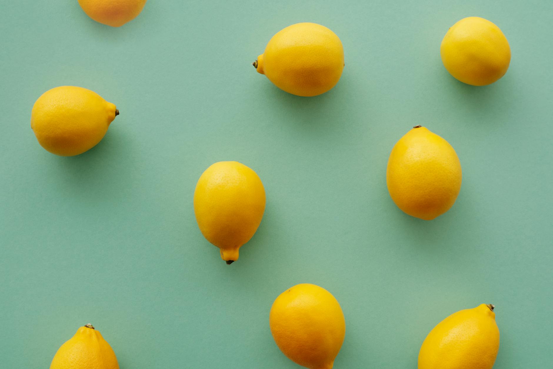 Bright yellow lemons arranged on a pastel green background, symbolizing fresh pleasure and vitality
