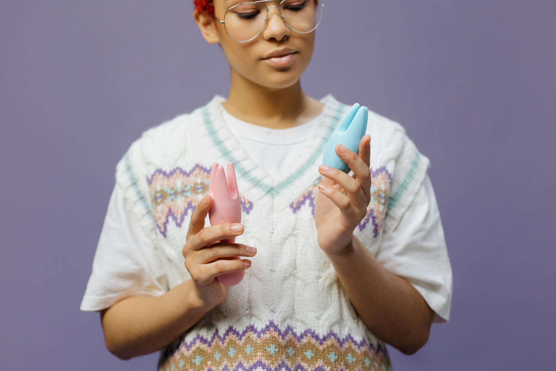 Woman holding a blue silicone vibrator in contemplative light, exploring self-pleasure and desire.