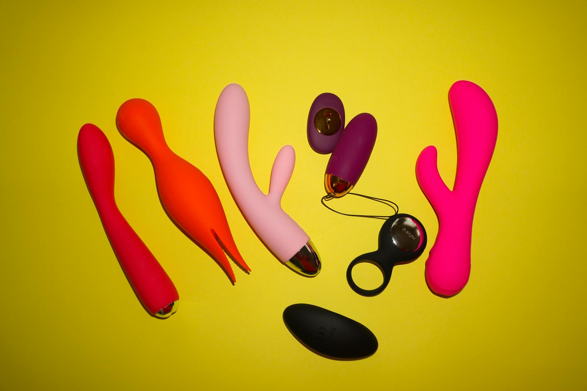 Colorful vibrators and sex toys displayed on a bright yellow background
